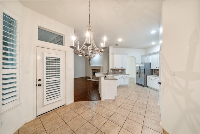 47 Dresden Pl, The Woodlands, TX 77382 - kitchen featuring stainless steel fridge, a peninsula, a chandelier, white cabinets, and recessed lighting