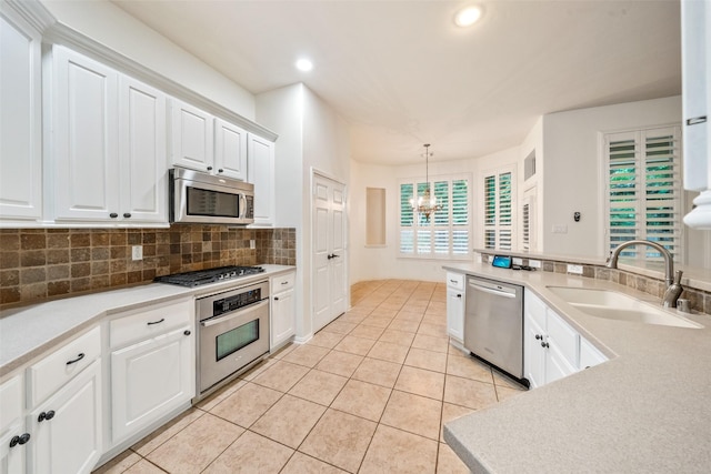 47 Dresden Pl, The Woodlands, TX 77382 - kitchen featuring stainless steel appliances, a chandelier, backsplash, light tile patterned flooring, and white cabinets