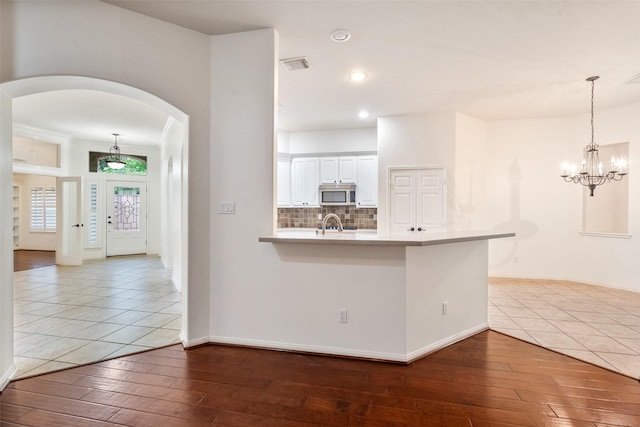 47 Dresden Pl, The Woodlands, TX 77382 - kitchen featuring stainless steel microwave, wood-type flooring, arched walkways, a peninsula, and recessed lighting