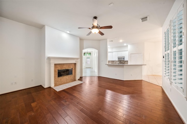 47 Dresden Pl, The Woodlands, TX 77382 - unfurnished living room with a ceiling fan, hardwood / wood-style floors, arched walkways, a tile fireplace, and recessed lighting