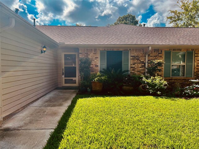 667 E Country Grove Cir, Pearland, TX 77584 - entrance to property with a yard, roof with shingles, and brick siding