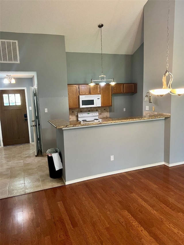 667 E Country Grove Cir, Pearland, TX 77584 - kitchen featuring white appliances, brown cabinetry, light wood-type flooring, backsplash, and hanging light fixtures