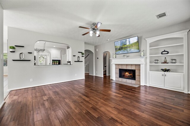 17518 Cypress Laurel St, Houston, TX 77095 - unfurnished living room featuring a ceiling fan, wood finished floors, a tile fireplace, and arched walkways