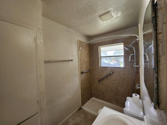 5535 Flamingo Dr, Houston, TX 77033 - bathroom featuring a textured ceiling, tile patterned floors, and tiled shower