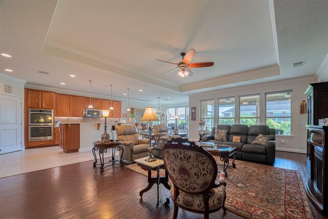 3903 Grand Fir Ct, Richmond, TX 77469 - living room featuring a tray ceiling, a ceiling fan, crown molding, light wood-style floors, and recessed lighting