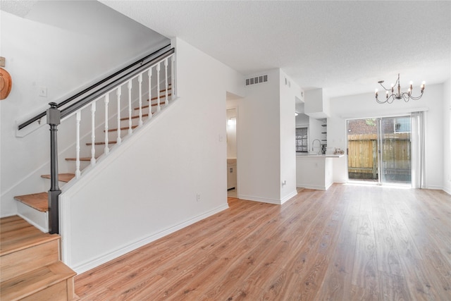 1515 Sandy Springs Rd Unit 2201, Houston, TX 77042 - unfurnished living room with wood finished floors, a chandelier, stairs, and a textured ceiling