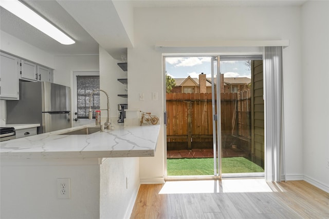 1515 Sandy Springs Rd Unit 2201, Houston, TX 77042 - kitchen with freestanding refrigerator, light wood finished floors, light stone countertops, and a peninsula