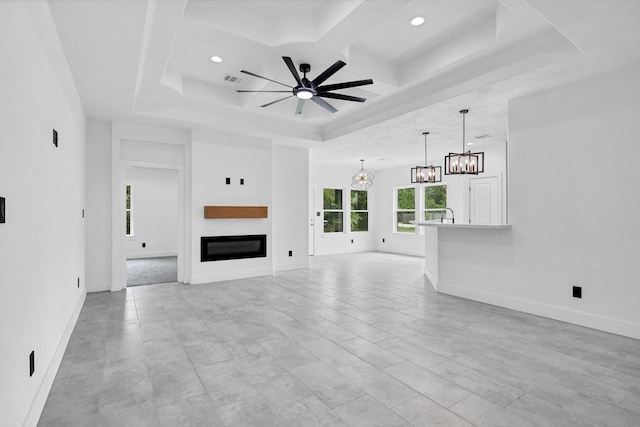 3220 Saint James Blvd, Beaumont, TX 77705 - unfurnished living room with a chandelier, a ceiling fan, coffered ceiling, a glass covered fireplace, and a tray ceiling