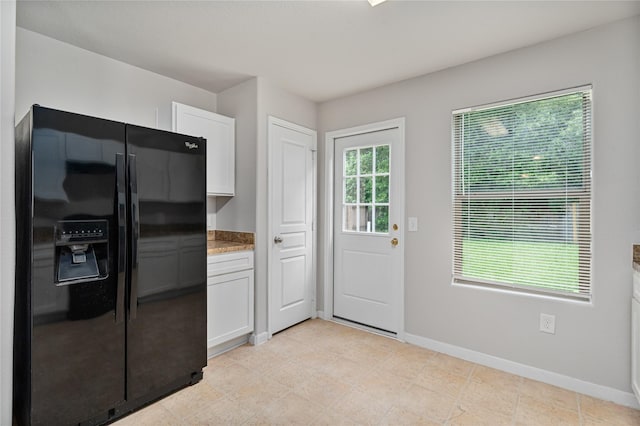 9826 Orchid Spring Ln, Houston, TX 77044 - kitchen with black fridge, white cabinets, and light stone counters