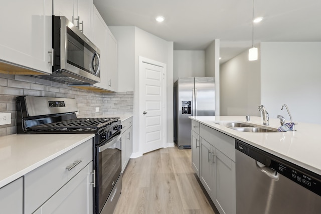8614 Lake Groove Ln, Baytown, TX 77523 - kitchen featuring appliances with stainless steel finishes, backsplash, light wood-style floors, light countertops, and pendant lighting