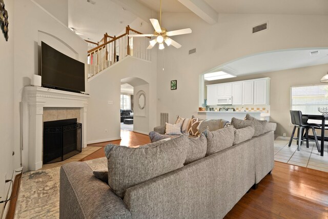 4146 S Webber Dr, Pearland, TX 77584 - living area featuring arched walkways, ceiling fan, a baseboard heating unit, beam ceiling, and a tiled fireplace