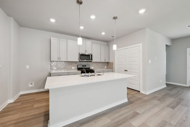 8615 Lake Groove Ln, Baytown, TX 77523 - kitchen with stainless steel microwave, range, light countertops, backsplash, and a center island with sink