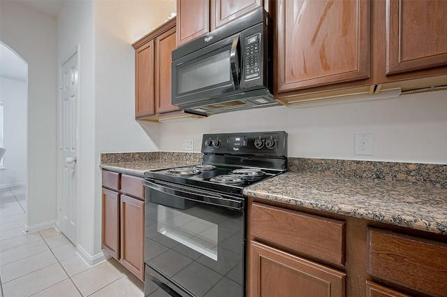 30914 Sweetwater Cir, Magnolia, TX 77355 - kitchen with black appliances, light tile patterned floors, arched walkways, brown cabinets, and dark countertops