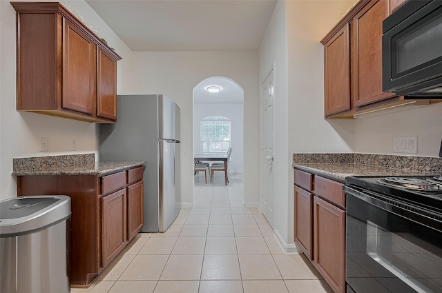 30914 Sweetwater Cir, Magnolia, TX 77355 - kitchen with black appliances, arched walkways, brown cabinetry, and light tile patterned flooring