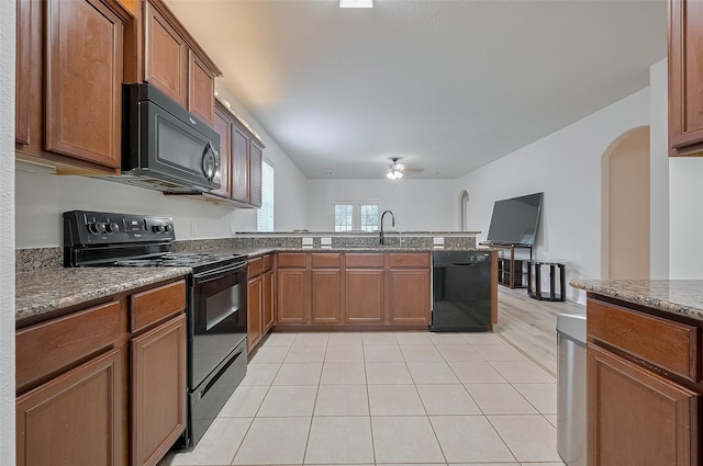 30914 Sweetwater Cir, Magnolia, TX 77355 - kitchen featuring black appliances, a peninsula, arched walkways, brown cabinets, and stone countertops