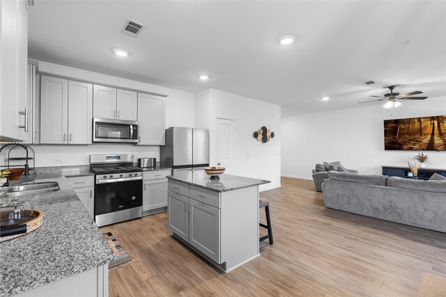 1100 Greenshank Dr, Katy, TX 77493 - kitchen featuring appliances with stainless steel finishes, gray cabinetry, open floor plan, a breakfast bar, and recessed lighting