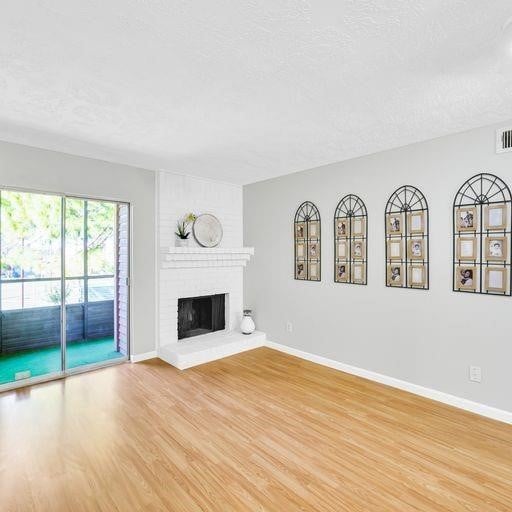 10555 Turtlewood Ct Unit 1803, Houston, TX 77072 - unfurnished living room featuring wood finished floors, a brick fireplace, and a textured ceiling