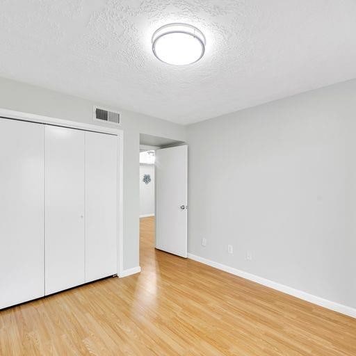 10555 Turtlewood Ct Unit 1803, Houston, TX 77072 - unfurnished bedroom with a textured ceiling, light wood-style flooring, and a closet