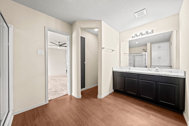 2015 Treasure Mountain Dr, Spring, TX 77388 - full bath with wood finished floors, double vanity, a ceiling fan, a textured ceiling, and a shower