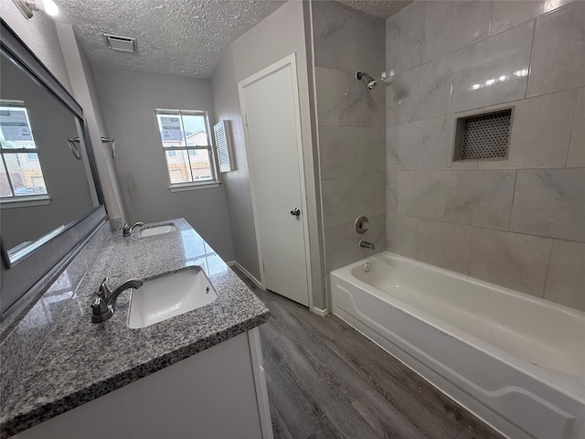 10052 Sharpton Dr, Houston, TX 77038 - bathroom featuring a textured ceiling, double vanity, wood finished floors, and shower / tub combination