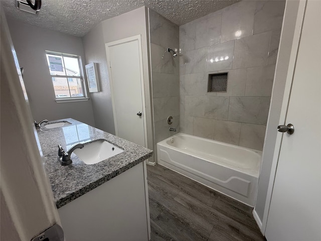 10052 Sharpton Dr, Houston, TX 77038 - bathroom with a textured ceiling, wood finished floors, double vanity, and bathing tub / shower combination