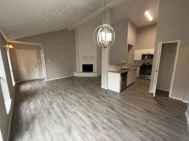 10052 Sharpton Dr, Houston, TX 77038 - kitchen with appliances with stainless steel finishes, open floor plan, a textured ceiling, a chandelier, and white cabinetry