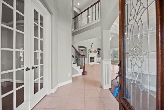 12207 Johns Enterprise Ct, Cypress, TX 77433 - foyer featuring french doors, tile patterned flooring, a warm lit fireplace, stairway, and a towering ceiling