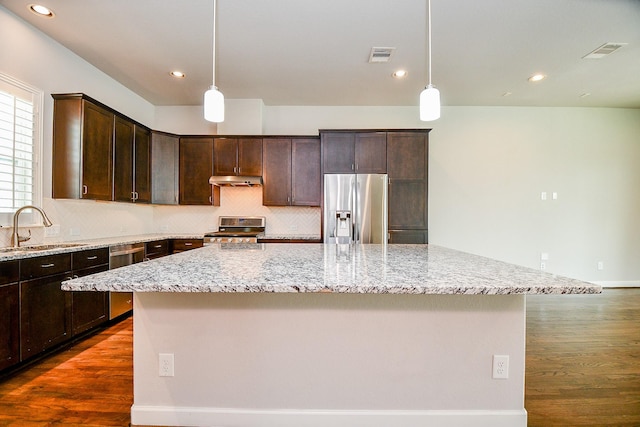 1909 Hickory St, Houston, TX 77007 - kitchen featuring stainless steel appliances, dark wood-style flooring, a kitchen island, dark brown cabinetry, and decorative backsplash