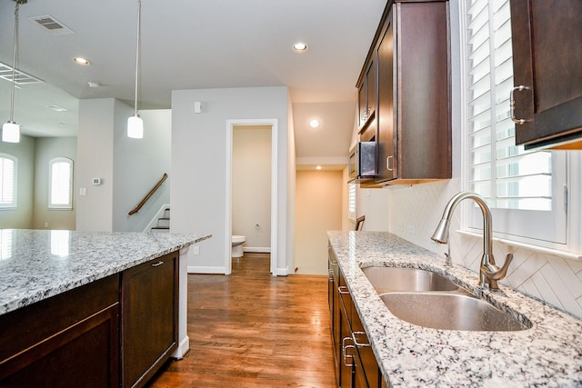 1909 Hickory St, Houston, TX 77007 - kitchen featuring dark brown cabinets, pendant lighting, dark wood-type flooring, light stone countertops, and recessed lighting