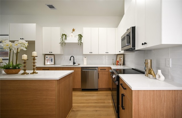 4009 New Orleans St A/B, Unit A/B Houston, TX 77020 - kitchen with appliances with stainless steel finishes, light countertops, decorative backsplash, light wood finished floors, and white cabinetry
