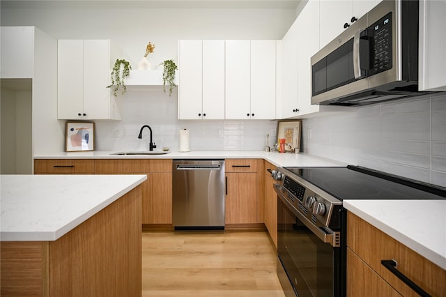 4009 New Orleans St A/B, Unit A/B Houston, TX 77020 - kitchen featuring stainless steel appliances, light wood-style flooring, tasteful backsplash, white cabinetry, and light stone countertops