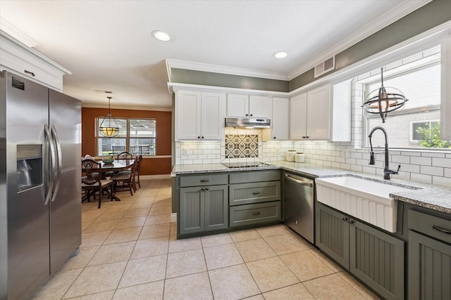607 Ellingham Dr, Katy, TX 77450 - kitchen featuring stainless steel appliances, under cabinet range hood, ornamental molding, tasteful backsplash, and white cabinetry