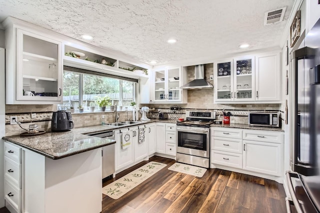 1902 Pepperrell Place Ct, Katy, TX 77493 - kitchen featuring appliances with stainless steel finishes, wall chimney exhaust hood, a peninsula, a textured ceiling, and white cabinets