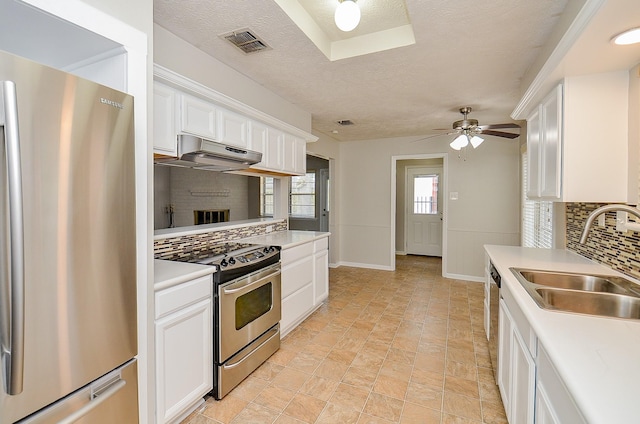 22127 Kerryblue Dr, Katy, TX 77450 - kitchen with appliances with stainless steel finishes, under cabinet range hood, tasteful backsplash, white cabinets, and light countertops