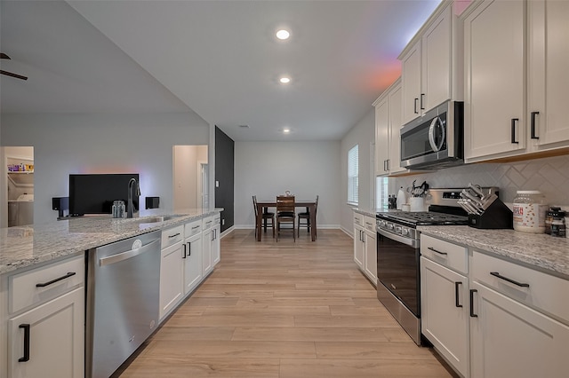 3213 Overfalls Dr, Santa Fe, TX 77510 - kitchen featuring appliances with stainless steel finishes, light wood finished floors, decorative backsplash, recessed lighting, and light stone counters