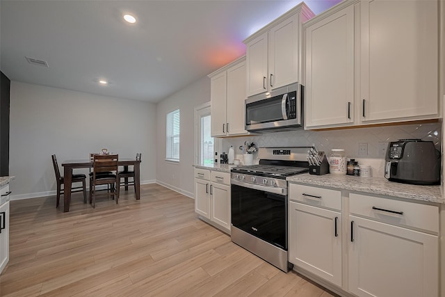 3213 Overfalls Dr, Santa Fe, TX 77510 - kitchen with stainless steel appliances, backsplash, light wood-style floors, recessed lighting, and white cabinetry