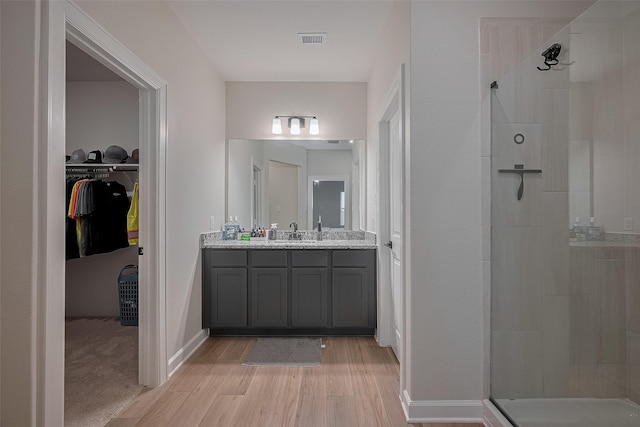 3213 Overfalls Dr, Santa Fe, TX 77510 - bathroom with tiled shower, wood finished floors, double vanity, and a walk in closet