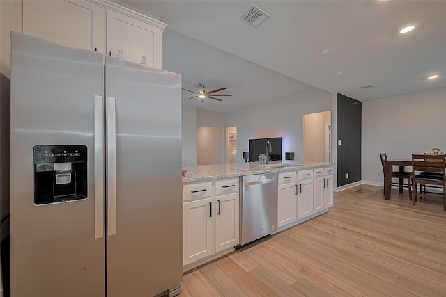 3213 Overfalls Dr, Santa Fe, TX 77510 - kitchen featuring stainless steel appliances, light wood finished floors, white cabinetry, ceiling fan, and light stone counters