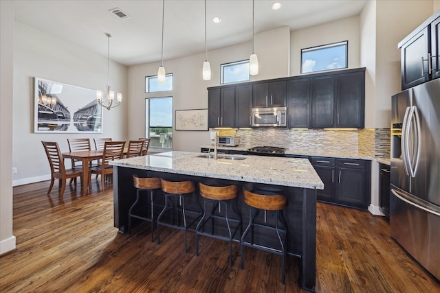 4102 Marina St, Houston, TX 77007 - kitchen featuring stainless steel appliances, light stone countertops, dark wood-style floors, a kitchen bar, and a chandelier