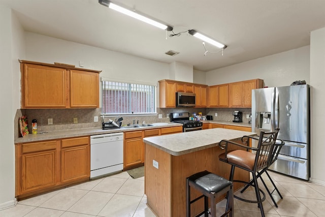 1327 Bartlett Cove Dr, Houston, TX 77067 - kitchen featuring appliances with stainless steel finishes, decorative backsplash, light countertops, light tile patterned floors, and a kitchen island