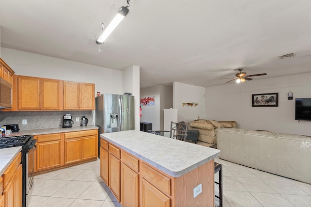 1327 Bartlett Cove Dr, Houston, TX 77067 - kitchen featuring stainless steel gas range oven, light tile patterned floors, a ceiling fan, light countertops, and a kitchen island