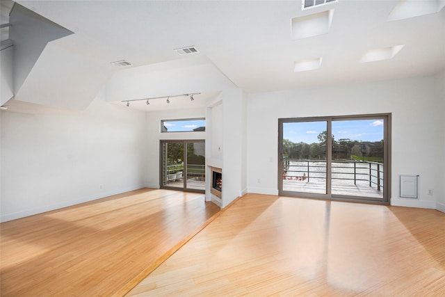 18405 Sandy Cv, Houston, TX 77058 - unfurnished living room featuring rail lighting, plenty of natural light, and wood finished floors