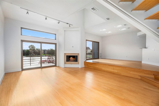 18405 Sandy Cv, Houston, TX 77058 - unfurnished living room with track lighting, light wood-style floors, a fireplace, plenty of natural light, and a high ceiling