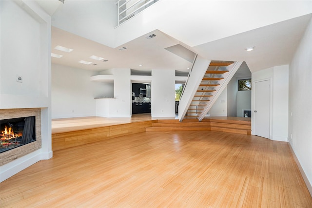 18405 Sandy Cv, Houston, TX 77058 - unfurnished living room with a lit fireplace, stairs, and light wood finished floors