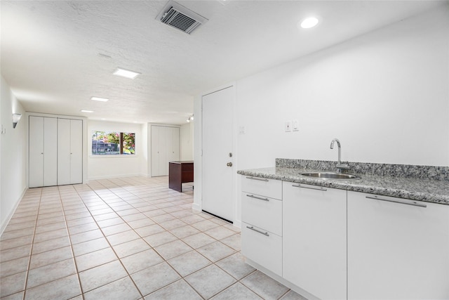 18405 Sandy Cv, Houston, TX 77058 - kitchen with white cabinetry, light tile patterned flooring, light stone counters, and a textured ceiling