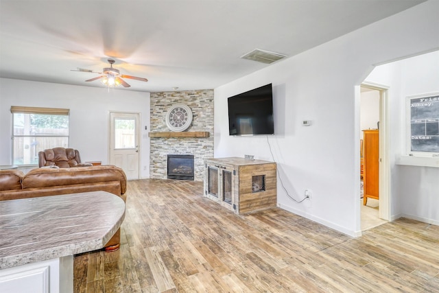 2726 Indigo Stone Ln, Katy, TX 77449 - living area with ceiling fan, light wood finished floors, a stone fireplace, and arched walkways