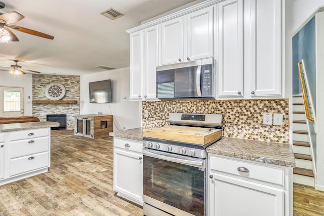 2726 Indigo Stone Ln, Katy, TX 77449 - kitchen with appliances with stainless steel finishes, a ceiling fan, backsplash, open floor plan, and light wood finished floors