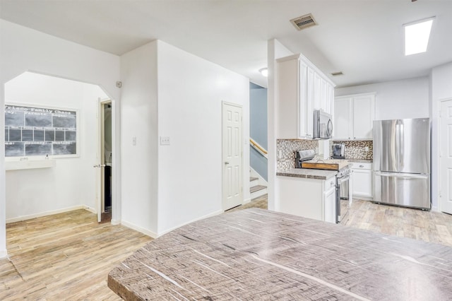 2726 Indigo Stone Ln, Katy, TX 77449 - kitchen with stainless steel appliances, light wood-style floors, decorative backsplash, white cabinets, and light countertops