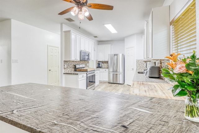 2726 Indigo Stone Ln, Katy, TX 77449 - kitchen featuring stainless steel appliances, a ceiling fan, tasteful backsplash, white cabinets, and light wood-style floors