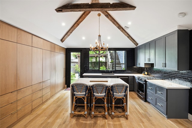 406 Bomar St, Houston, TX 77006 - kitchen with stainless steel range, a chandelier, a kitchen bar, a center island, and light wood-style floors